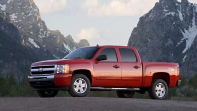Promo photo of a red 2011 Chevrolet Silverado 1500 pickup truck parked in front of snow-capped mountains.