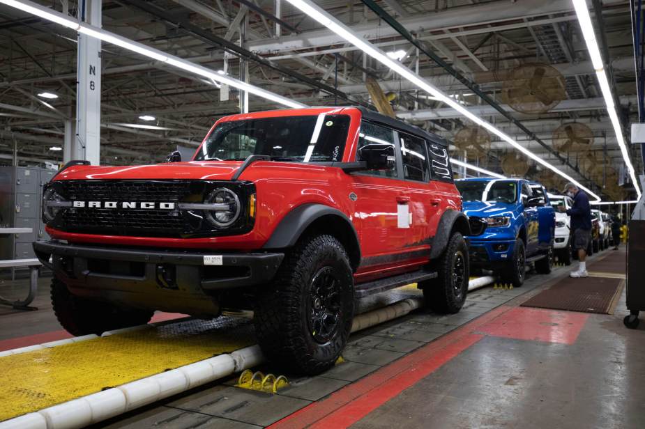 The red Ford Bronco rolls down an assembly line in front of a blue Ford Ranger.