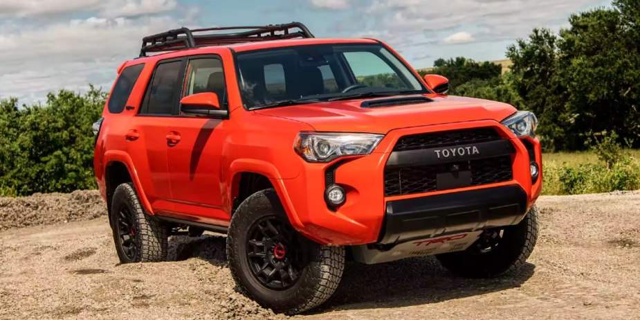 An orange Toyota 4Runner midsize SUV is parked off the street.