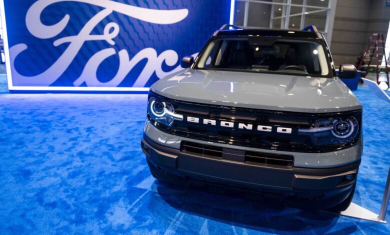 Front-on view of grey Ford Bronco Sport in front of a large Ford logo set on blue carpet.