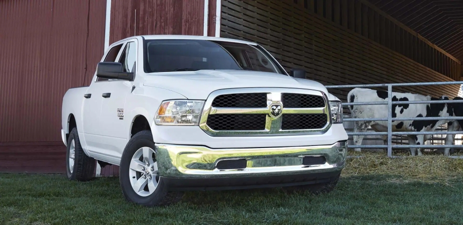 An oversized white Ram Classic truck next to a barn.
