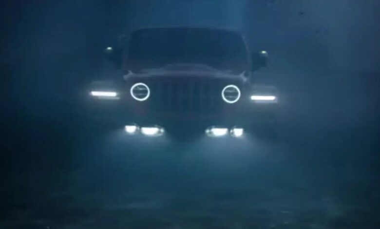 Stellantis promo photo of a modern Jeep Wrangler driving underwater, its headlights illuminating the ocean.