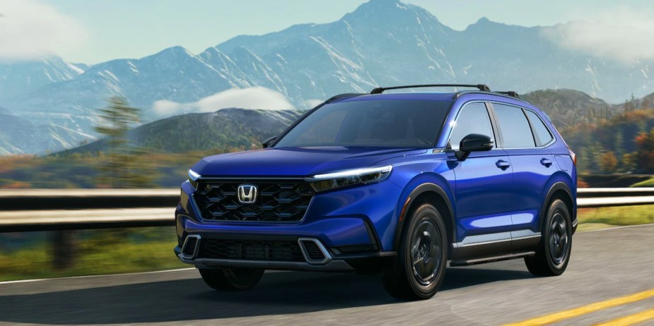 A small blue 2023 Honda CR-V SUV is driving on the road. 