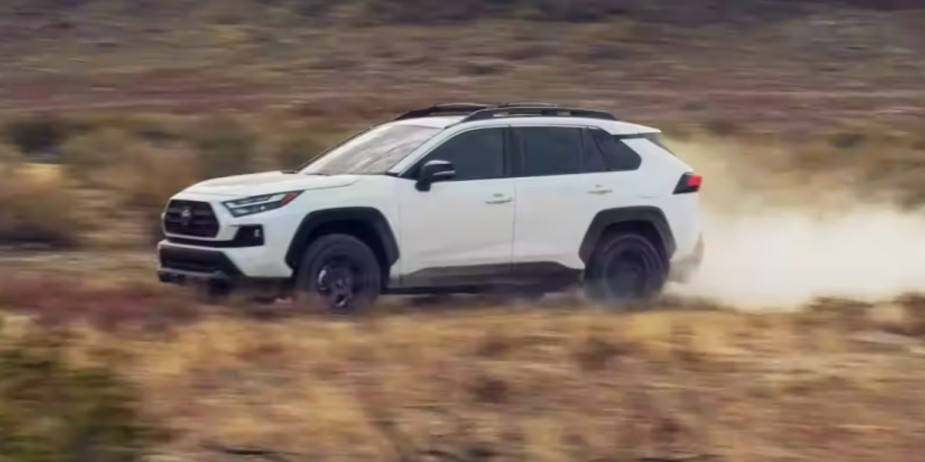 A small white 2023 Toyota RAV4 SUV is driving off-road. 