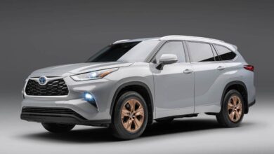 Silver 2023 Highlander Hybrid with bronze wheels sits in a grey photo space.