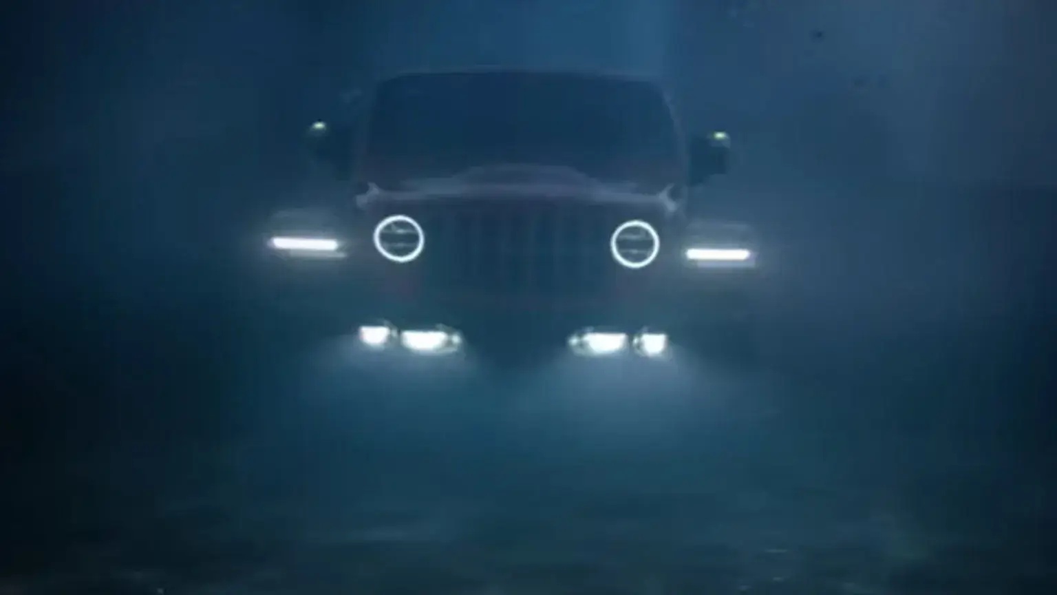 Stellantis promotional photo of a modern Jeep Wrangler driving underwater, with its headlights illuminating the ocean.