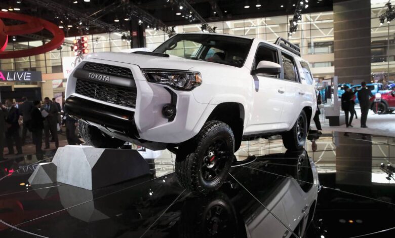 A new Toyota 4Runner in white propping up one wheel on a black floor at an auto show.
